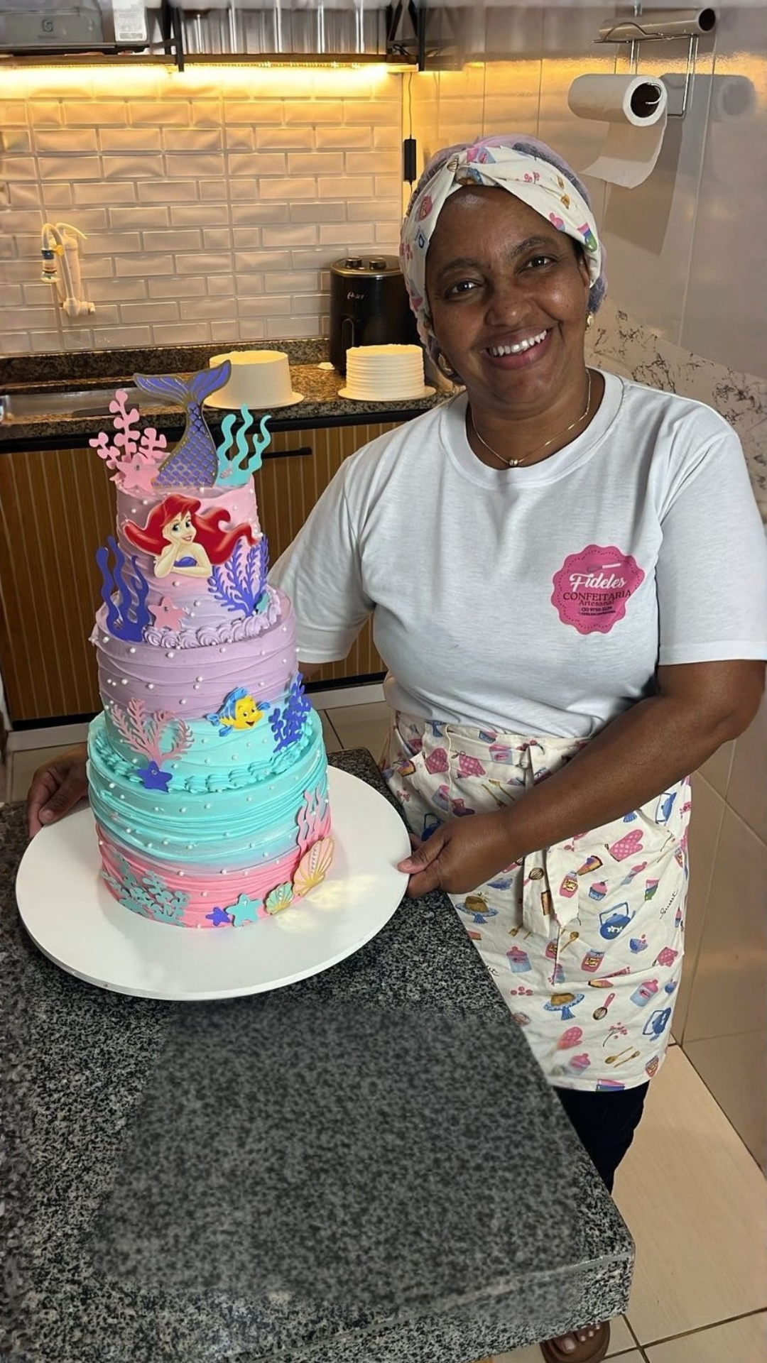 Mônica Fideles segurando um bolo artesanal da FIDELES CONFEITARIA